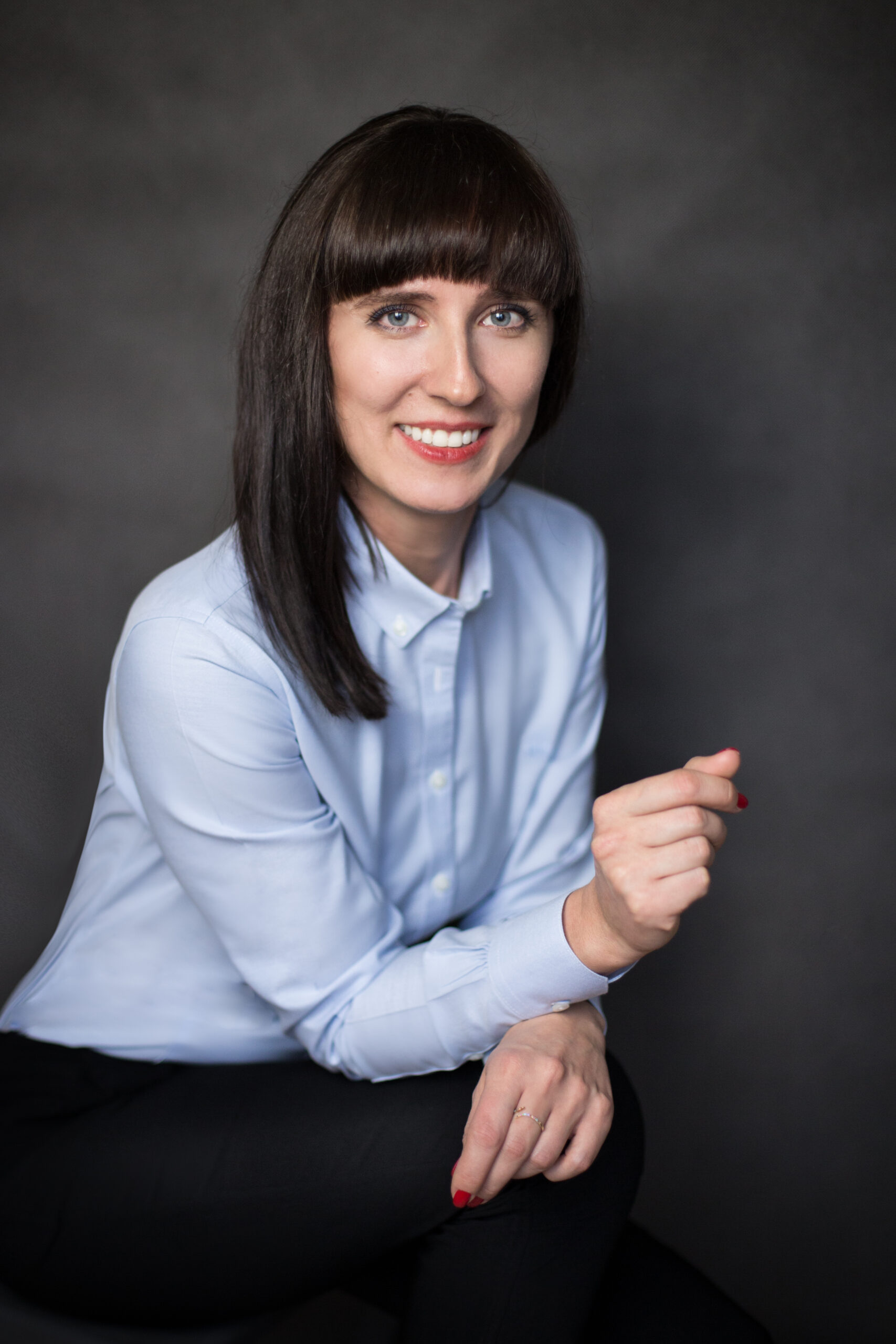 Portret biznesowy kobiety w błękitnej koszuli na ciemnym tle